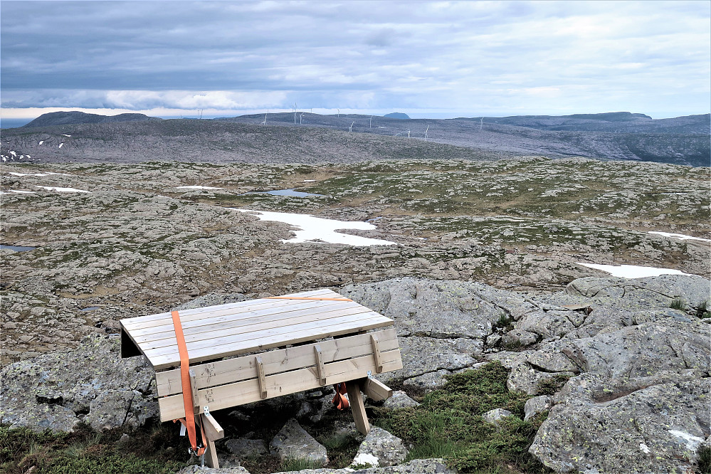 Ein benk og nokre få kasser og planker sto på toppen i "intet" Ramsskredfjellet 793/Bremanger med utsikt til vindmøller! Noko paradoksalt & til undring! Ser rett og slett ingen meining i dette.