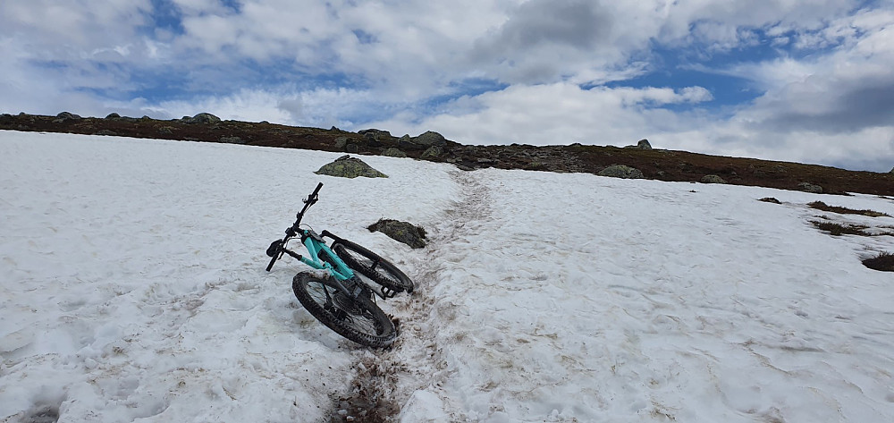 Det lå igjen noen snøfonner på nordsiden av Nevelfjell, og da ble det å dytte sykkelen opp over snøen
