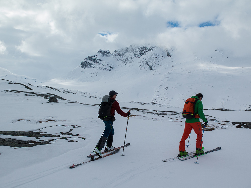 Skiene er på og vi fortsetter videre opp til Ryptinden. Åselitindan med Djeveltanna og Store Åselitinden ruver i bakgrunnen. Fremdeles omkranset av skyer.