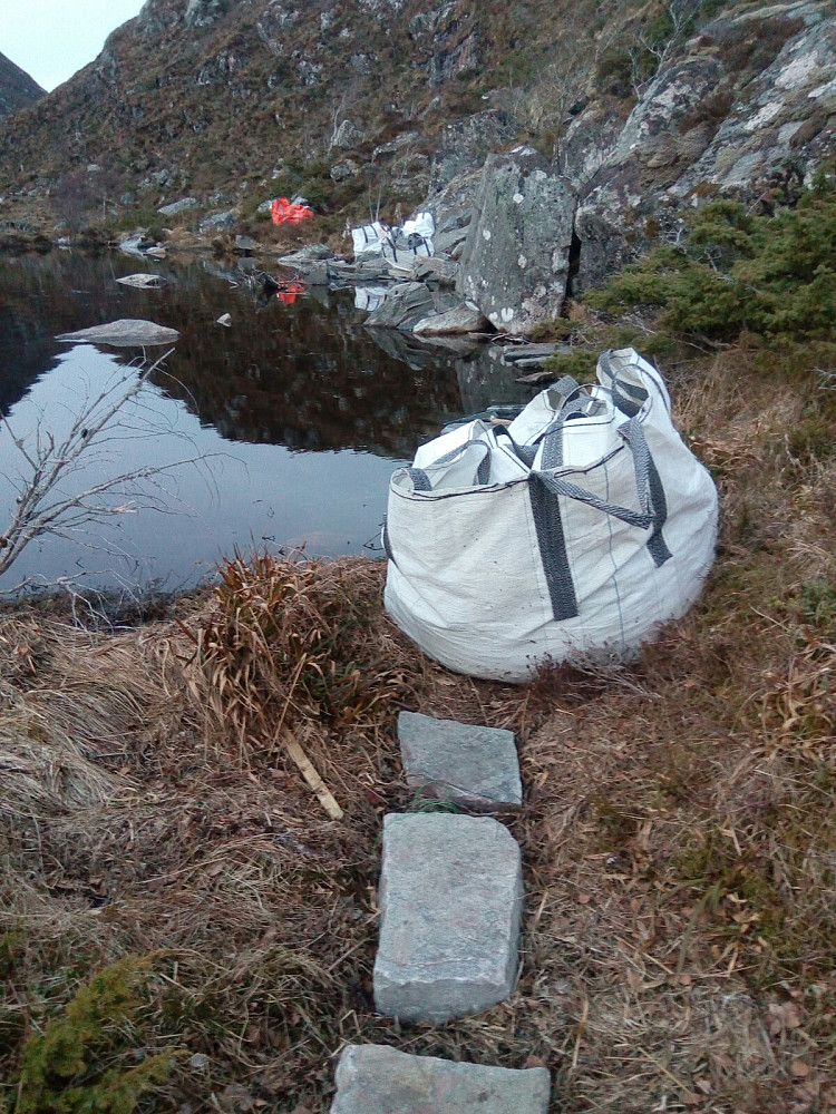 Flere storsekker med steinheller ved vannet
