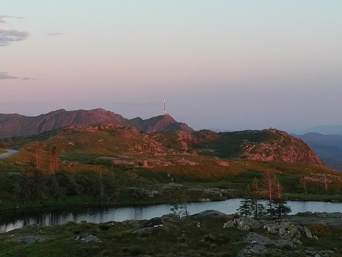 Bilde av Blåmanen tatt fra Rundemanen, oppe ved den gamel sendestasjonen. Den har en rekke knauser og topper, og flere små tjern innimellom disee. Ulriken sees i bagrunnen.