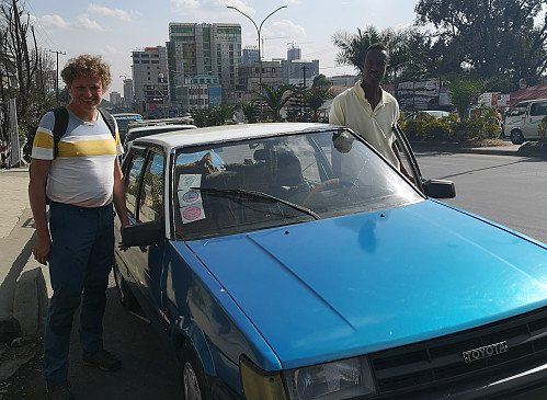 #9: In Churchill Avenue with the taxi driver Fikedu and his Toyota Corolla. His taxi is painted in blue and white; which is typical for traditional cabs in Ethiopia. Fikedu is a little bit expensive compared to Uber taxis and the similar, but he is extremely reliable. If he promises to wait for you, he'll wait for you; and if he promises to pick you up, he does exactly that.