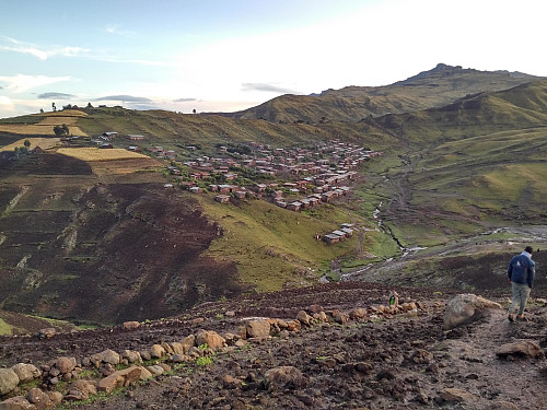 #60: The village of Arkwasiye and Enyew on the muddy trail leading down to it. Our tents are barely visible to the right of the village; i.e. on the other side of the little creek.