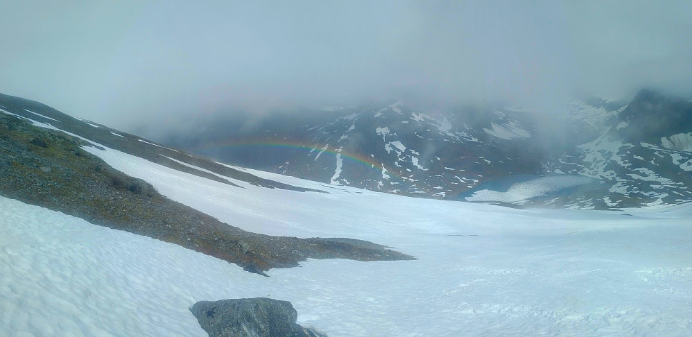 #2: When I reached about 1000 m.a.m.s.l., there suddenly was a gap in the clouds, and for a few minutes the sun was shining in the south west, just above the east ridge of Mount Alnestinden; and there behind me, in the north east, was a rainbow with beautiful colours. Lake Alnesvatnet is seen in the background.