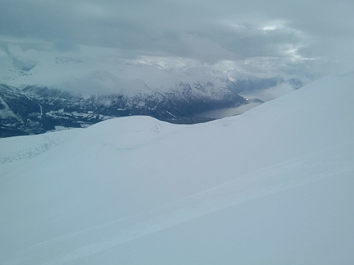 #9: Back down under the clouds. The inclination of the downhill slopes from Mount Kyrkjetaket is about 30°, with short segments >35°; hence it's necessary to take care and avoid going there on days with a high risk of avalanches.