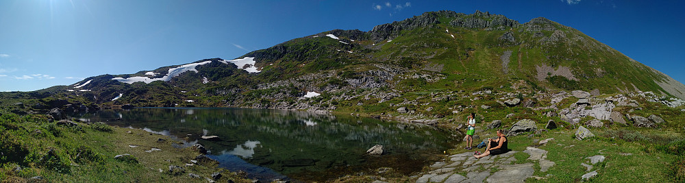 Image #21: Panorama of the larger of the two lakes on the plateau above the caves. This lake has no visible outlet upon the ground; the water emerging from it is running in fissures in the mountain, and is contributing to the formation of the river that is running through the caves of the "Troll's Church". In the background are seen Trolltindan [i.e. The "Troll Peaks"] and Mount Stordalstinden [i.e. The "Great Valley Peak"]. If weather is nice when you go hiking in these mountains, this is a fabulous spot for your lunch break.