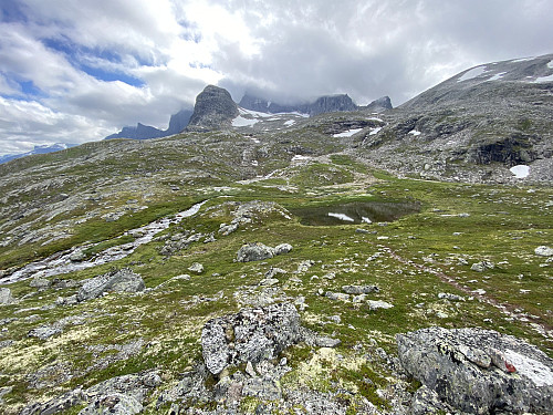 Image #12: A creek, a pond, and some mire in the notch between Mount Norafjellet and Mount Adelsfjellet. The glacier Adelsbreen is visible in the background.