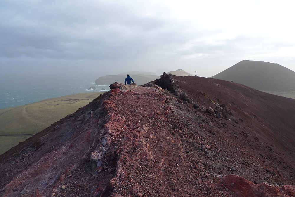 Toppunktet på Eldfell til venstre. Lars på vei tilbake langs kanten. Vulkanfjellet Helgafell i bakgrunnen til høyre