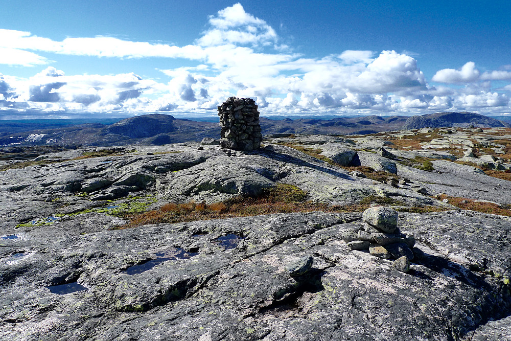 Toppområdet på Sveinsheii. Trig-punktet med liten varde og strenger i forgrunnen. Hovedvarden på høyeste sted i bakgrunnen. Roan til venstre for varden.