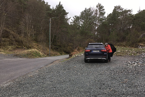 Grei parkering langs Bjørnavegen sør nær en bakketopp