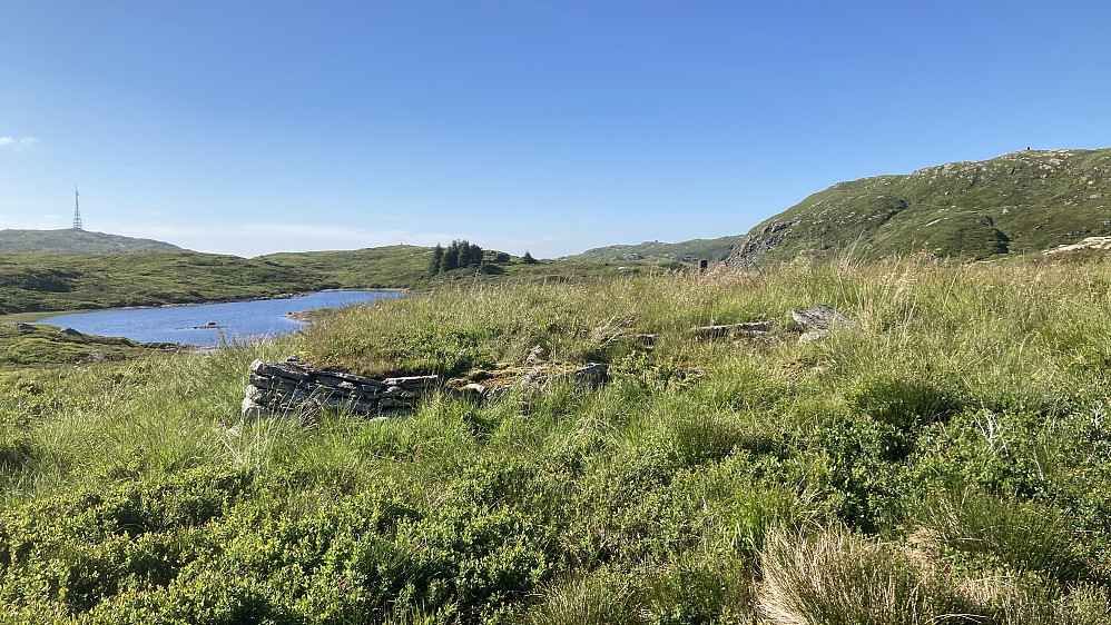Mur på stedet der hytten Solglytt sto. Langelivatnet og masten på Rundemanen i bakgrunnen