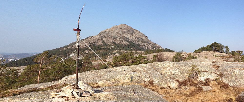 I forgrunnen trigmerket på Skarpafjellet. Toppen i furulunden til høyre. Lyderhorn i bakgrunnen