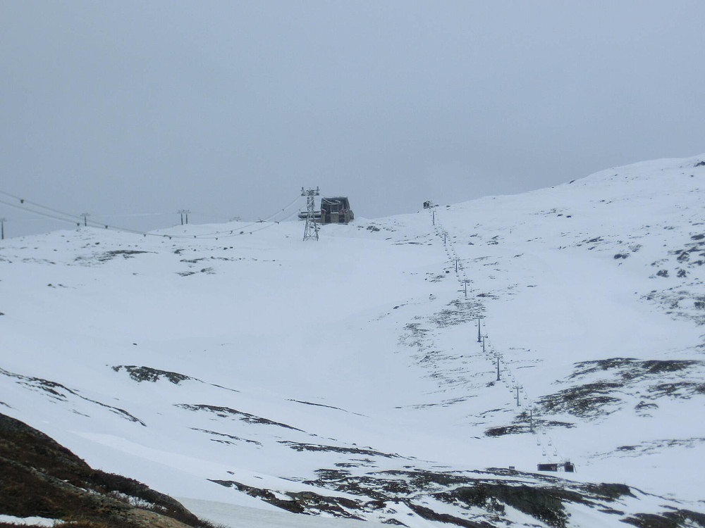 Her ser vi toppen av liften. Vinden har tiltatt litt mere en de 6 m/s som YR.no lovte. Ingen overaskelse det forsåvidt.. Vi skal prøve å ta en rute med mindre snø helt til venstre i bildet.