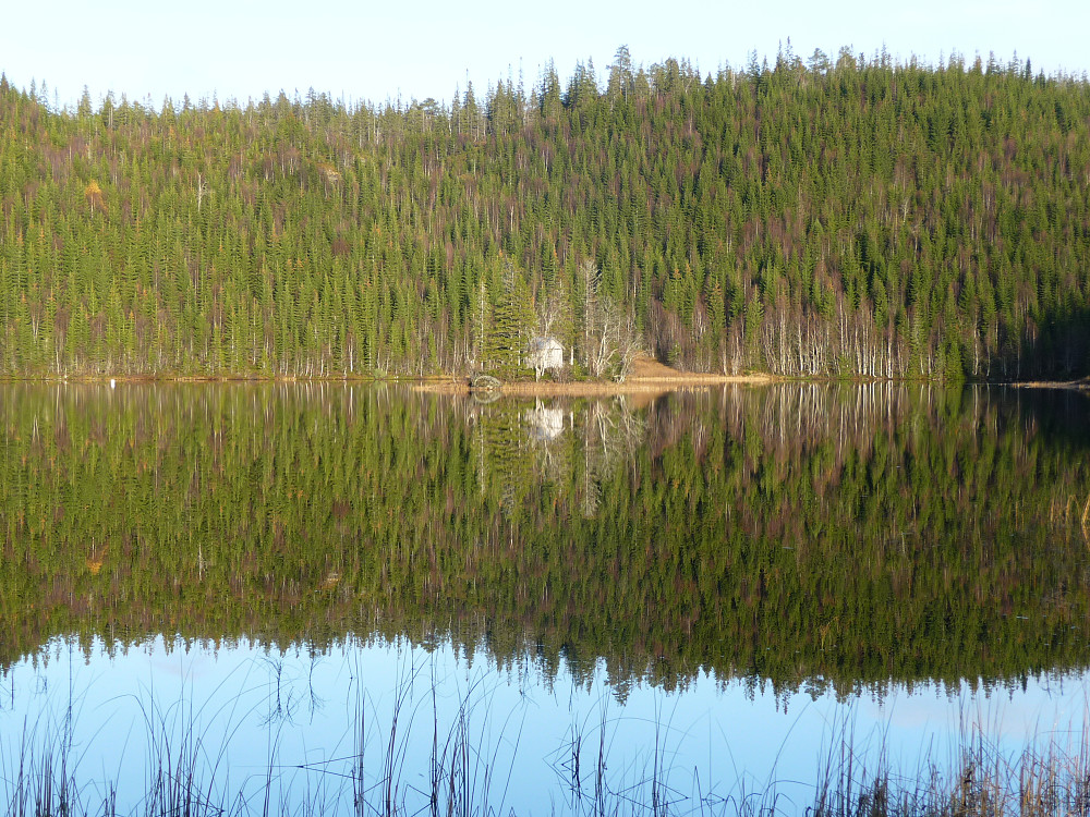 Holmen i Storkartjern med speilblankt vann og høstlige farger.