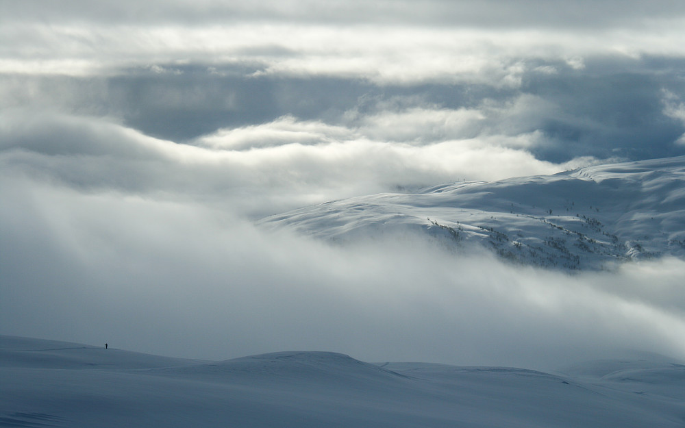 Fjellene på andre siden av Sogndalsdalen kommer til syne gjennom skyene.