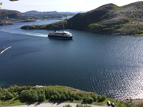 Utsikt fra standplass i Oppdrettsveggen. Bilparkeringa ses nede til høyre, oppe i midten sees brua over til Stokkøya. Nordgående hurtigrute hilste oss med luren og vi vinket ivrig tilbake.