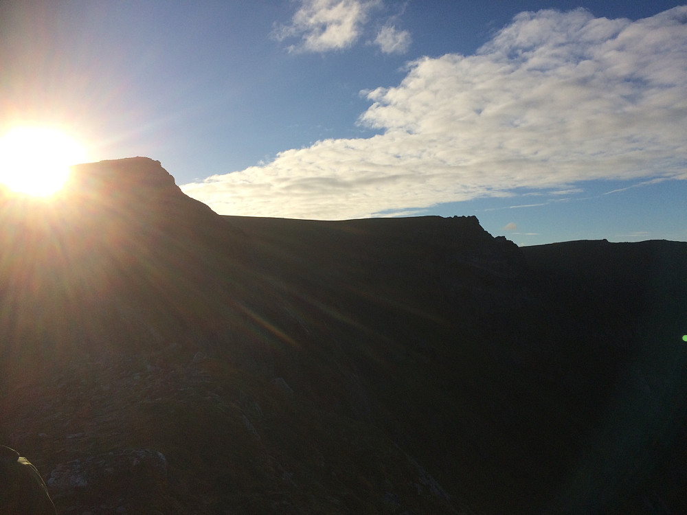 Toppen av Måtind med strålende sol bak.