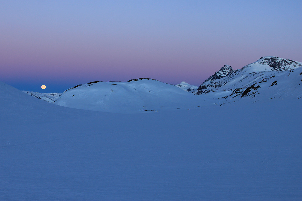 Månen går ned i fjellene på sydsiden av Bygdin. Snart skinner dagens første solstråler på Torfinnstindane (2120 moh) og Nørdre Kalveholotinden (2019 moh).