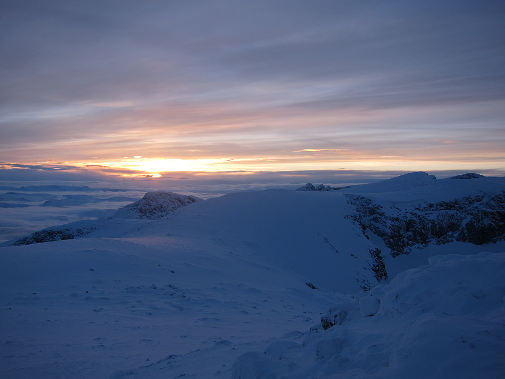 Sola går ned, sett fra toppen av Rasletind. Torfinnstinder stikker opp litt til høyre fra midten av bildet.