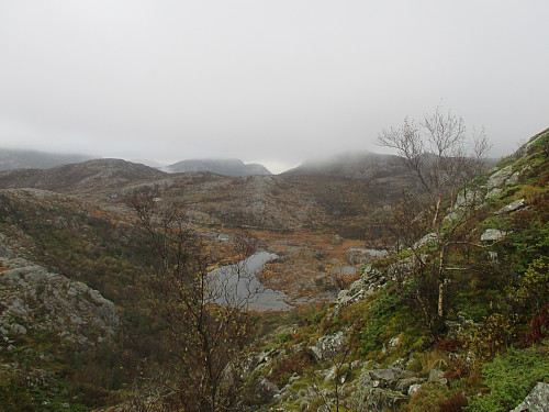 I oppstigninga mot Grimsåsen frå Ulvaskardet med tilbakeblikk mot Blokkelitjødnane og ruta frå grusvegen. 558-toppen er den høgaste som går opp i skydekket