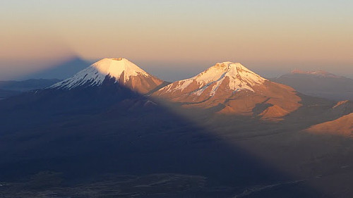 Soloppgang naer toppen av Sajama (legg merke til skyggen). Her ser man vulkanene Parinacota (6348m) and Pomerape (6282m) paa grensen til Chile