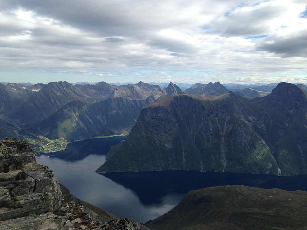 Hjørundfjorden drøyt 1500 meter under. Slogen litt til hø for senter, Store Smørskredtinden 2-puklet topp til hø herfor. Jakta avrundet topp helt til hø i forgrunnen