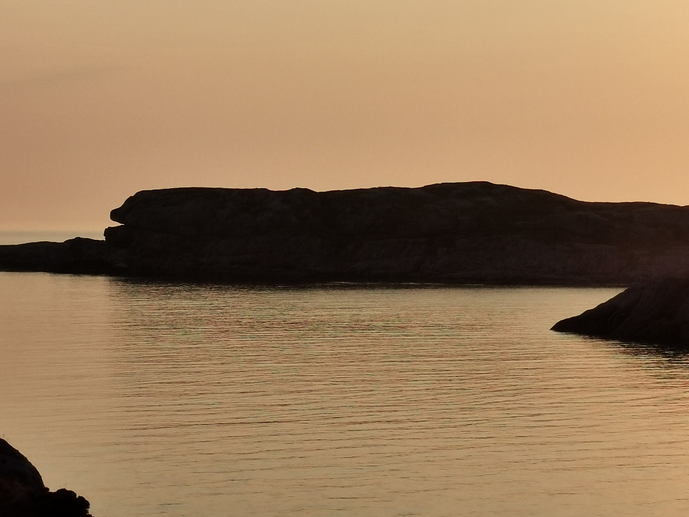 Rossøy. Ser ut som en spekkhogger(uten ryggfinne..) med halvåpen munn. Munnen er en heller hvor de to sjeldne, og rødlistede, bregnene havburkne og hjortetunge vokser. 