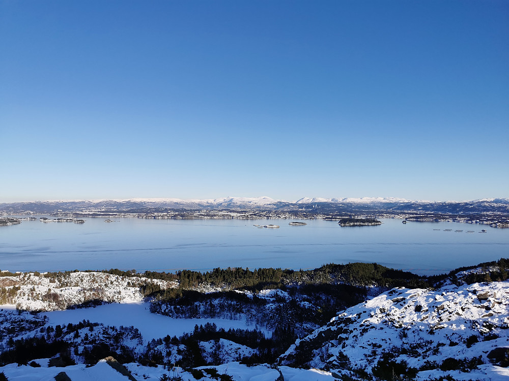 Speilblank fjord. Innbydende byfjell i øst. 
