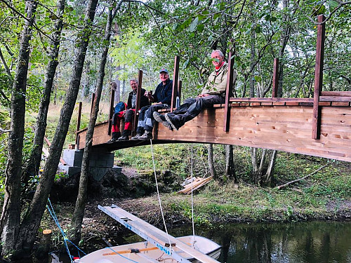 Dugnadsgruppa dingler med beina etter at bjelkene og brodekket har kommet på plass.