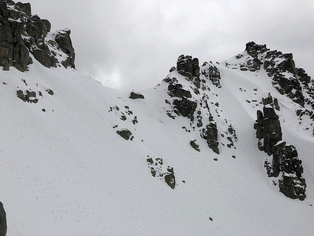 Flanken som må traverseres østover, etter den bratte snørenna. Innsteget til ryggen er på snøen til venstre for fjellet til venstre for sadelen
