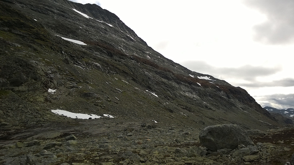 "nord­over fjellsiden i retning en nokså flat utlø­per i karakteristisk rødfarget stein, på ca. 1560 moh" Denne røde rampa i sørvestflanken på Uranostinden er lett å identifisere fra Urdadalsbandet.