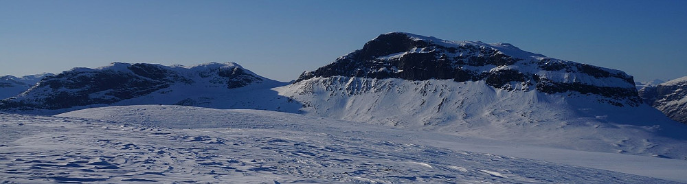 Grindane sett fra Smådalsfjellet i sørøst. Sommerstien går opp den tydelige sadelen midt i bildet, og deretter til høyre (litt på baksiden) og opp til topps.