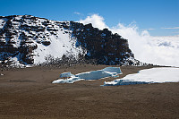 På vei opp til Reusch Crater med utsikt ned i krateret med det lille som er igjen av Furtwanglerbreen. Uhuru Peak ses i bakgrunnen, med ruta opp fra krateret.