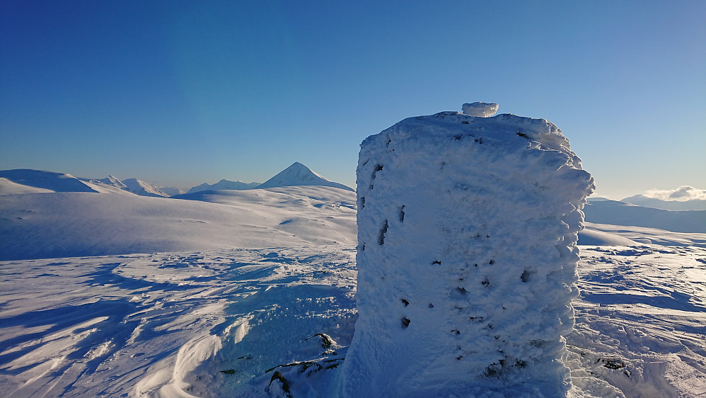 Varden på Blåfjellet med Tromsdalstind stikkende opp i bakgrunnen og blåmannen til venstre