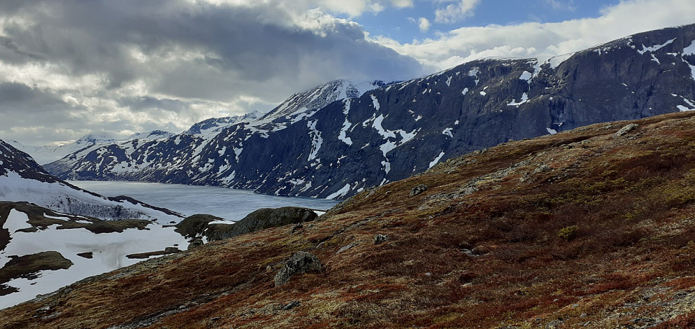 Gjende er fortsatt islagt. Besseggen sett fra stien opp mot toppen. Besshøe skjuler seg i en kjole av sky i bakgrunnen