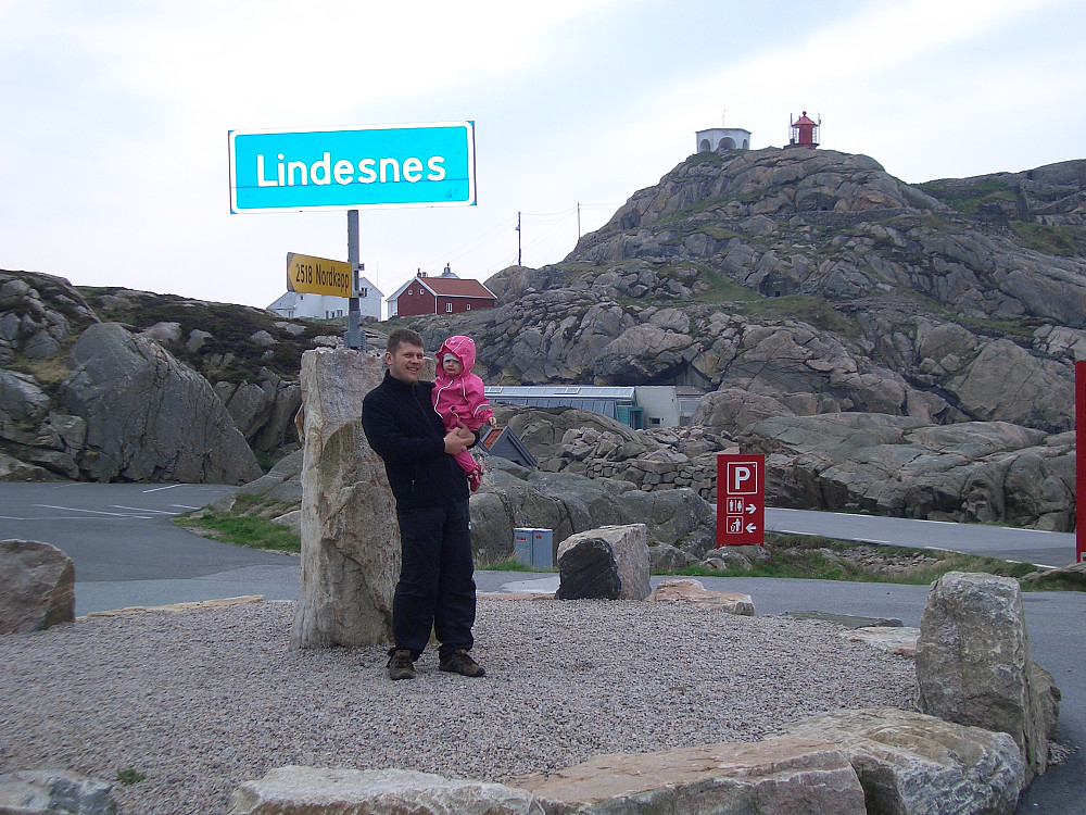 Nok ett turistfoto for albumet vårt. Jeg slapper av i armen til pappa mens vi står under skiltet som forteller hvor vi er.