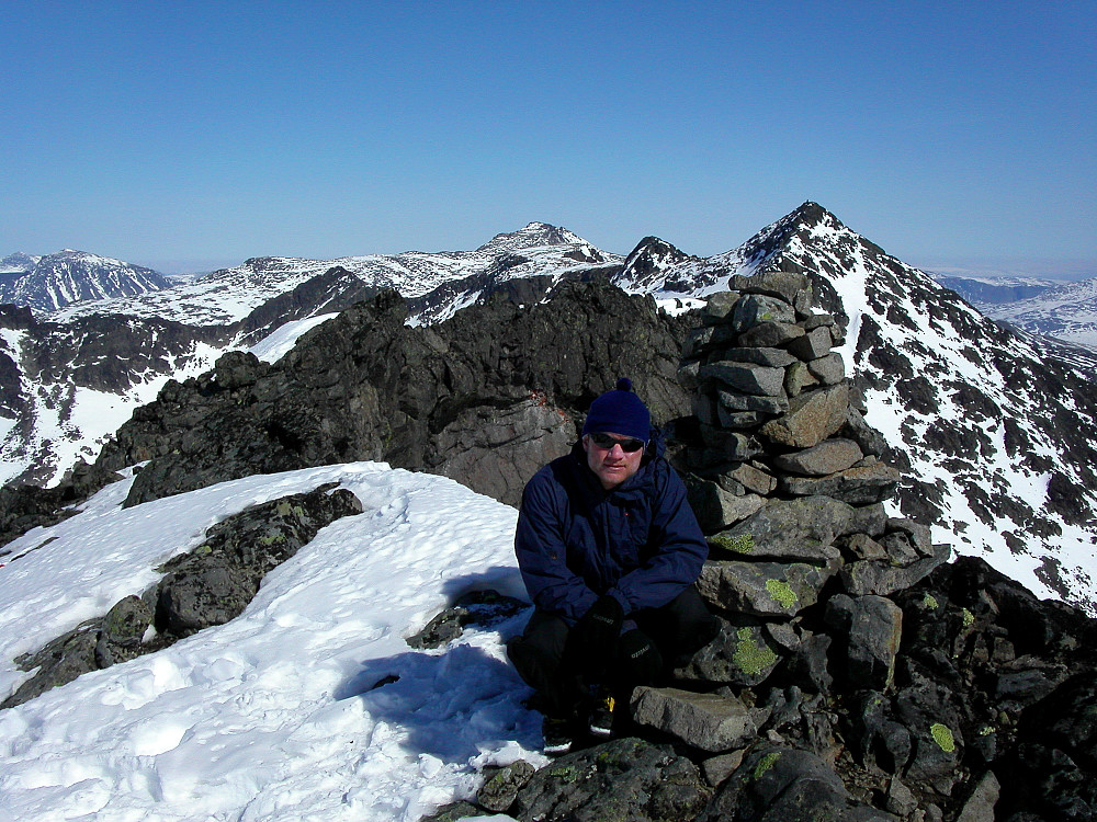 21.04.2003 - Per Rune ved toppvarden på Vestre Leirungstinden (2250). Utsikt mot nordøst. Pyramidetoppen til høyre er Austre Leirungstinden (2288). Langt bak til venstre ses Besshøe (2258), som ikke har mye snø igjen.