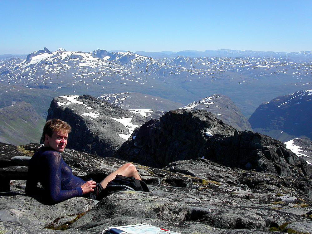 13.07.2003 - Johan Kristian slapper av på Store Midtmaradalstinden (2056). Utsikt mot sørøst. Toppen av Vetle Midtmaradalstinden (2017) er nærmest til høyre.