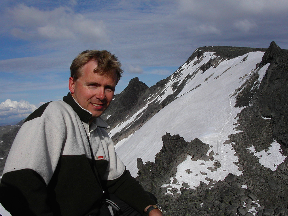 24.07.2004 - God følelse å sitte på toppen av Søre Nål på Knutseggen (2072)! I bakgrunnen oppe til høyre er Nørdre Knutsholstinden (2185). Midt i bildet ses Burchardts Tind (2129). Våre spor er godt synlige i snøen til høyre.