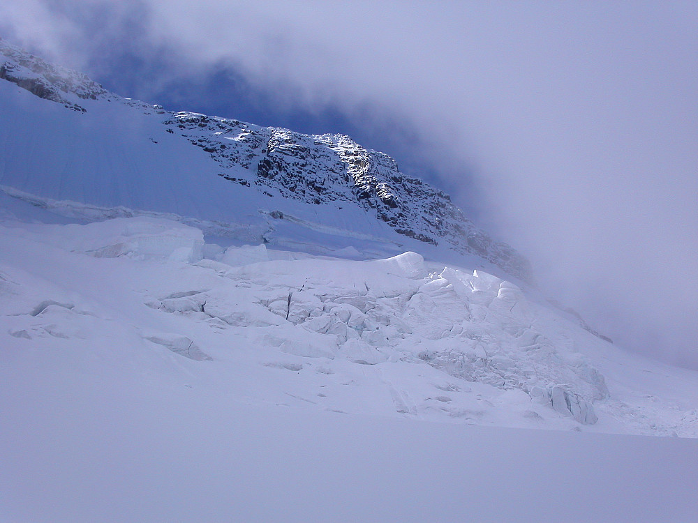 03.09.2004 - Styggedalstindane kommer til syne høyt over oss når tåka endelig letter på Gjertvassbreen. Her ses Vesttoppen (2377).