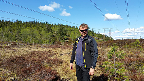 15.05.2016 - Vi står under høyspenten sør for Trettekollen (607), som er åsen bak til venstre. Vi gikk oppover i åpningen i bjørkeskogen litt til venstre for meg.