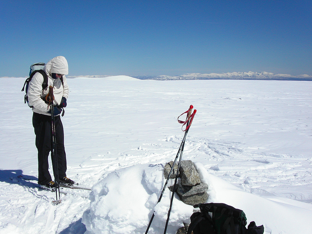 27.05.2006 - Per Rune ved toppvarden på den helt flate Store Trollsteinhøe (2201). Her var det like før vi dro fram pilkeutstyret... Langt bak til høyre skimtes Rondane.