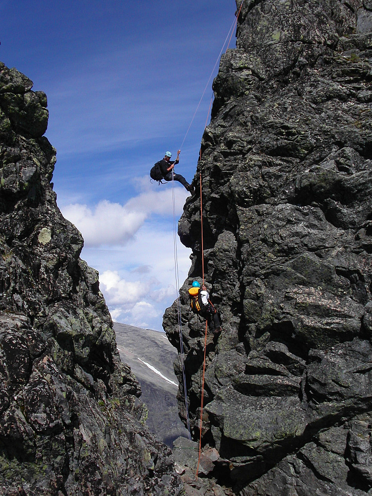 26.07.2006 - Erik og Torgeir i dagens siste rappell, ned i det trange skaret mellom Vestre (2085) og Midtre Torfinnstinden (2110). Torgeir, med gul sekk, ble hengende en stund for å fotografere oss 3 andre mens vi rappellerte forbi.