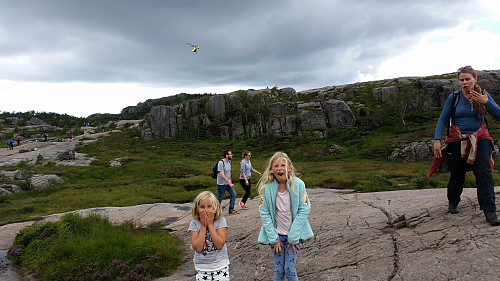 06.08.2016 - På stien til Preikestolen, på strekningen langs nord- og nordvestsiden på Neverdalsfjellet (706). I bakgrunnen lander et ambulansehelikopter like øst for Neverdalskarfjellet (584).