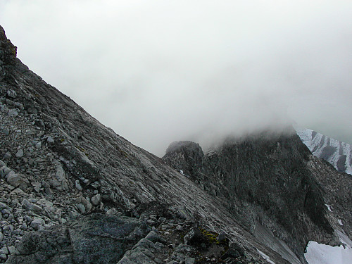 26.08.2006 - Fra toppryggen på Store Austanbotntinden ser vi ned mot vestryggen. Vestre Austanbotntinden (2100) stikker opp i tåka til høyre i bildet.