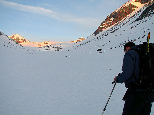 Fremdeles skygge nede i Tverrådalen. Et av dagens mål, Nørdre Bukkeholstinden (2149), lyser opp av dagens første solstråler i bakgrunnen til venstre.