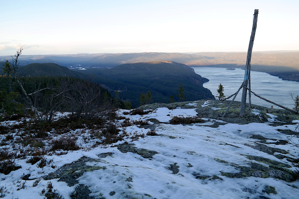 Flott utsikt fra trig.punktet, som ligger 100 meter nordøst for toppen på Elsrudkollen (757). Bildet tatt mot N/NØ. Innsjøen Sperillen nede til høyre. Åsen midt i bildet som sola så vidt skinner på toppen av, er Ramberget (542). Tettstedet Nes skimtes lenger bak til venstre.