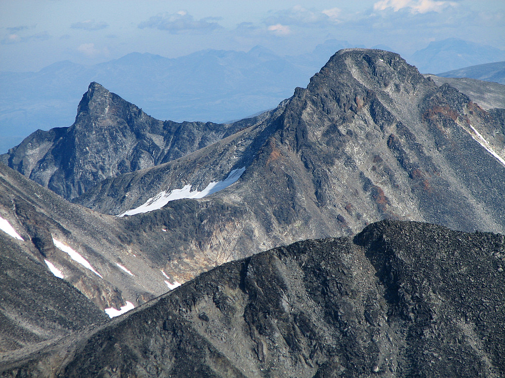 Zoom mot Store Veotinden (2240, til venstre) og Austre Memurutinden (2301, til høyre). Nærmest til høyre er Memurutinden V2 (2238). Helt bakerst i det fjerne, skimtes Rondane. Bildet er tatt fra Store Hellstugutinden (2346).