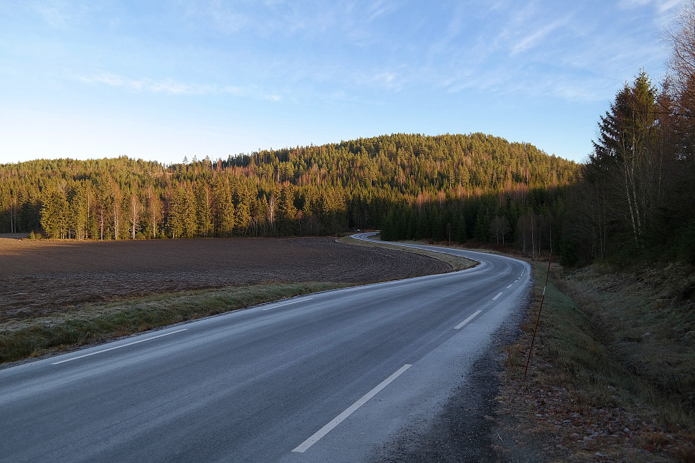 Vandring langs en småglatt Fv229 helt i starten. Bakerst er Høgåsen (234). Bilen kan ses der veien forsvinner inn i skogen.