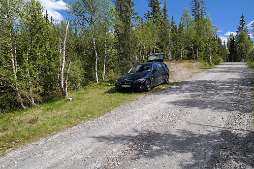 Parkeringslommen i Skjerbrekkdalen. De reserverte plassene for hytteeierne er bakenfor bilen, til høyre. Stien går inn i skogen på andre siden av bilen.